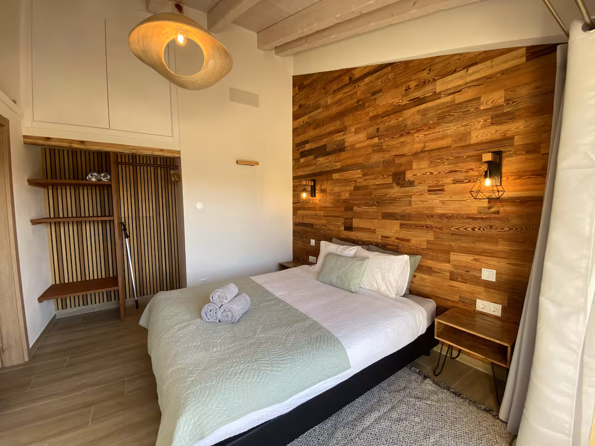 Slaapkamer met houten wand en tweepersoonsbed